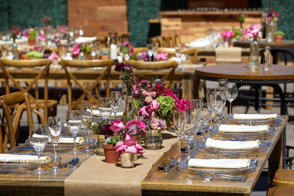 Outdoor celebration tables with pink flowers and rustic wood chairs